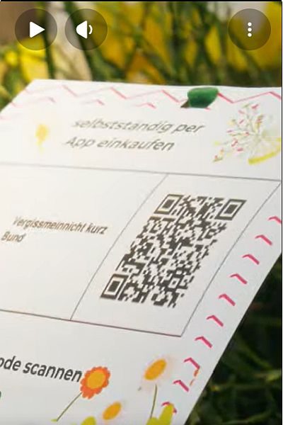 Klaus Hüskes steht in der Gärtnerei Hüskes zwischen Pflanzen und erklärt, wie Kundinnen und Kunden mit der Lokbest-App selbstständig einkaufen und bezahlen können.